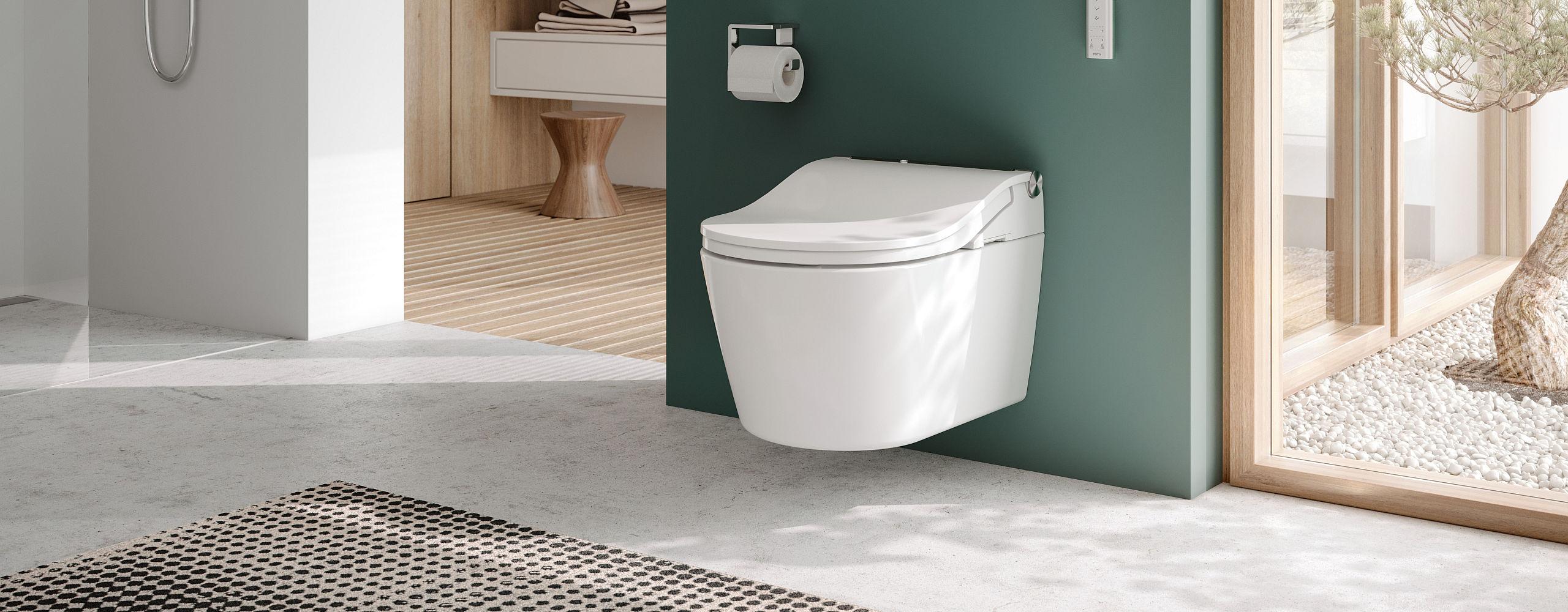 Ein modernes Badezimmer mit einem wandhängenden TOTO-Washlet, das vor einer grünen Wand montiert ist. 