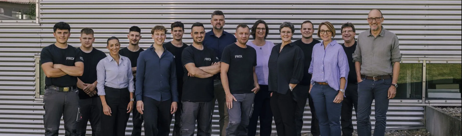 Das Team des bad un heizung Familienbetriebs FRICK steht vor dem Firmengebäude und lächelt in die Kamera.