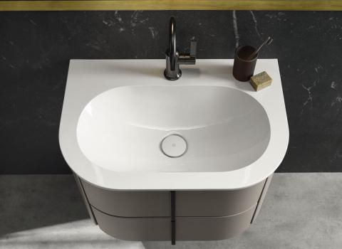 Ein kompakter Einbauwaschtisch mit einem glänzenden, weißen Becken, das in eine minimalistische Arbeitsplatte eingelassen ist. Der schwarze Wasserhahn fügt sich harmonisch in das moderne Design ein.