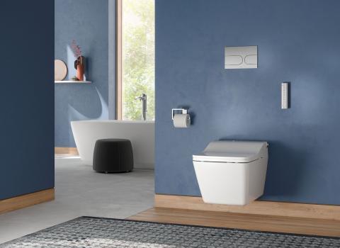 Großes Badezimmer mit blauen Wänden, einem wandhängenden TOTO-SW-WC und einer freistehenden Badewanne im Hintergrund.