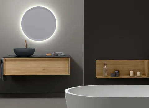 Modernes Badezimmer von Stocco mit rundem LED-Spiegel, Waschtisch aus Holz, schwarzer Aufsatzschale und freistehender Badewanne.