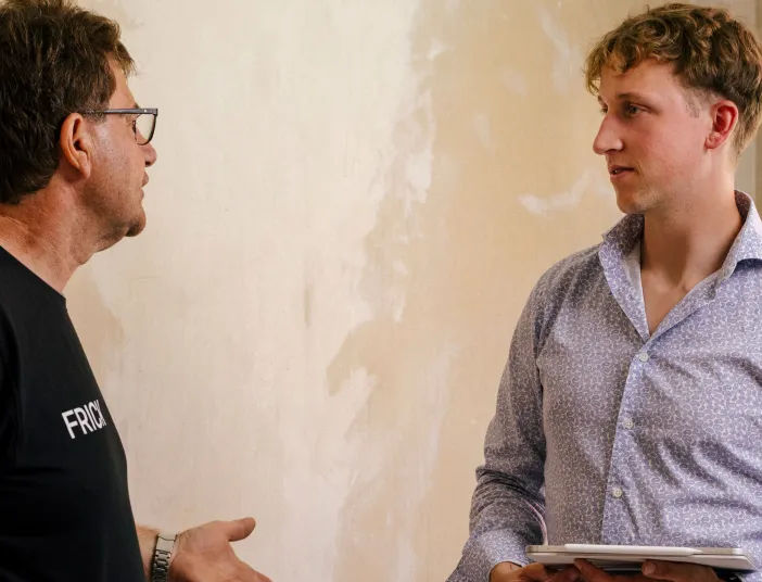 Ein Handwerker bespricht Baustellendetails und Planung mit dem Kunden vor Ort.