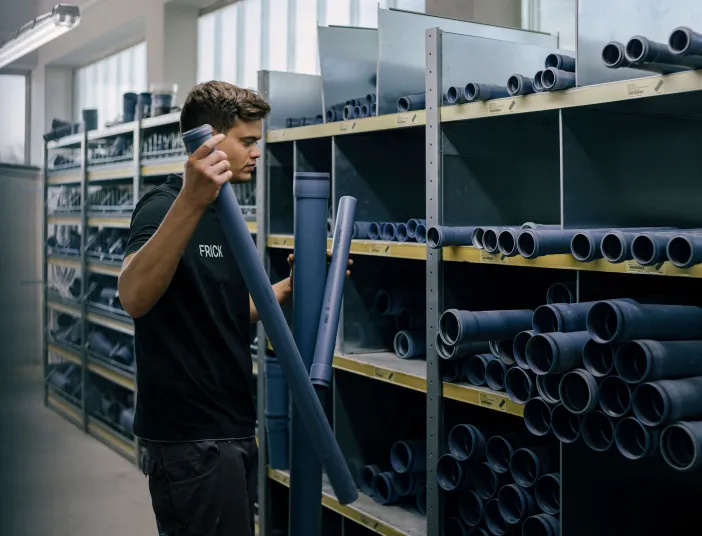 Sanitärfachmann wählt Kunststoffrohre im Lager für die Arbeitsvorbereitung aus.